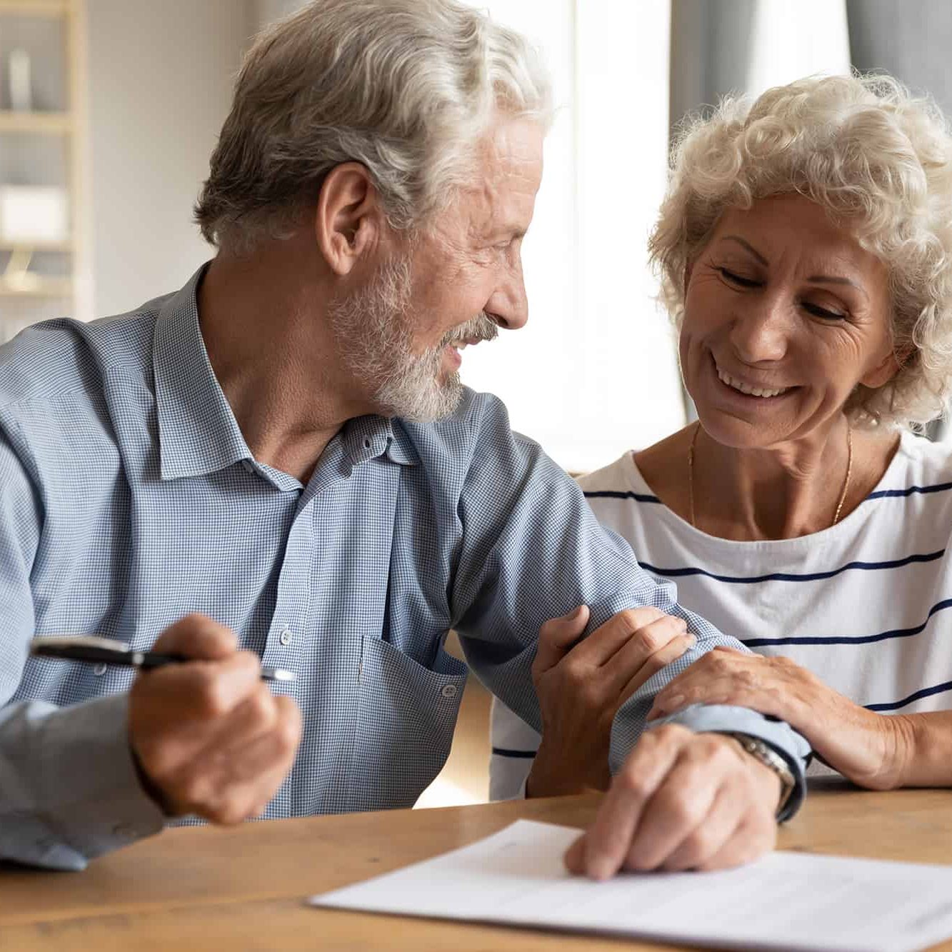 70s couple sit at table indoor discuss agreement term and condition feels satisfied make financial deal ready to sign contract, bequeath savings and property to their children or grandchildren concept