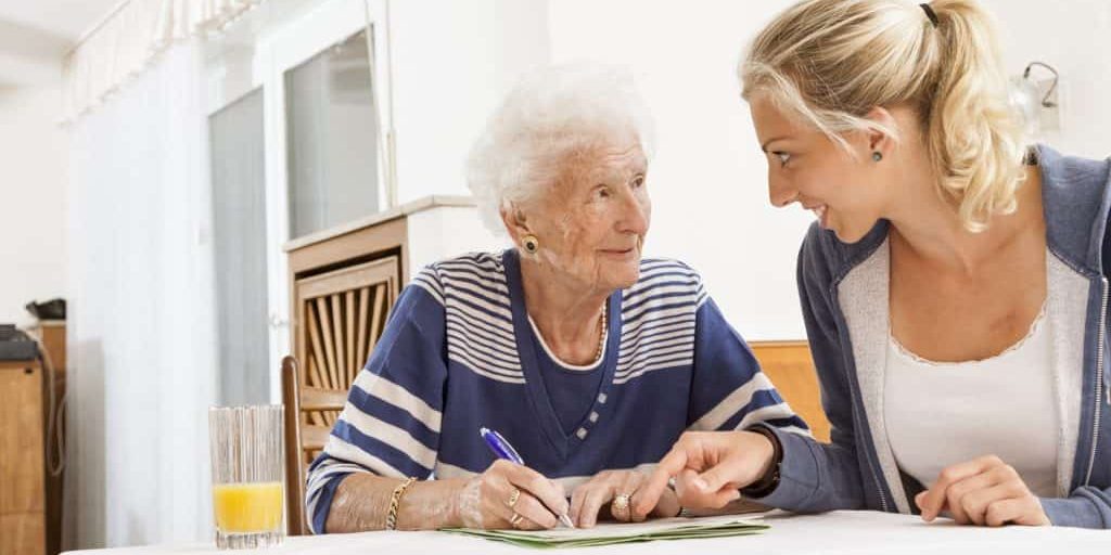young woman helping senior woman, 91 years old, with paperwork